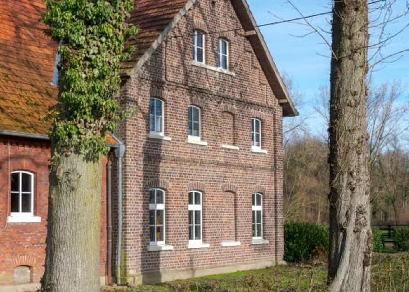 Älteres Backsteinhaus mit klassischen Fenstern als typische Illustration einer früheren Bauphase